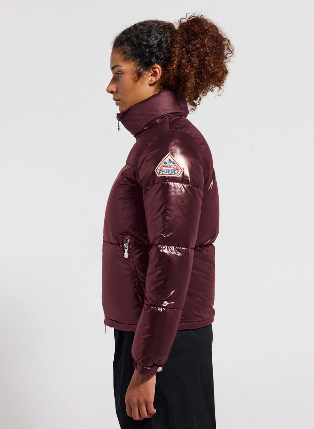 Vue de profil d'une doudoune brillante de coloris bordeaux avec col montant, matelassage horizontal et poches zippées.